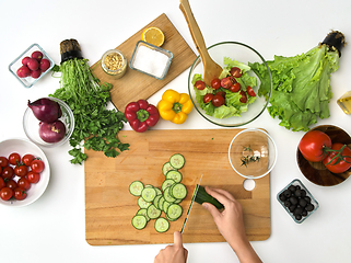 Image showing hands chopping cucumber on cutting board