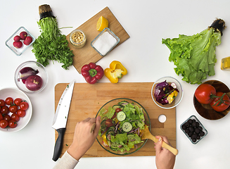 Image showing hands cooking vegetable salad on kitchen table