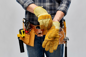 Image showing builder with working tools putting gloves on