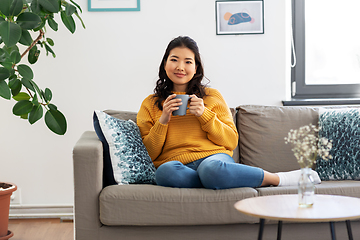 Image showing smiling asian young woman drinking coffee at home