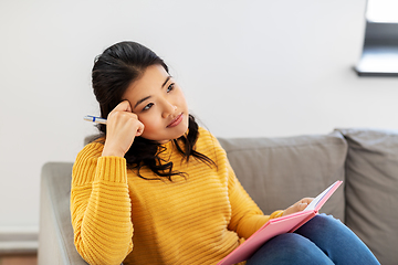 Image showing asian woman with diary sitting on sofa at home