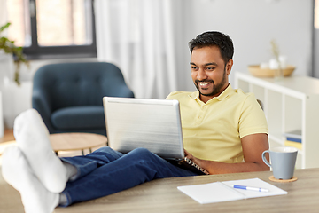 Image showing man with laptop resting feet on table at home