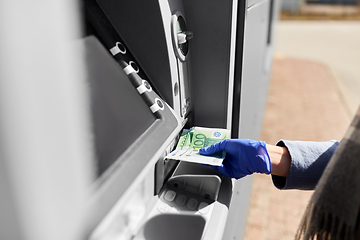 Image showing hand in medical glove with money at atm machine