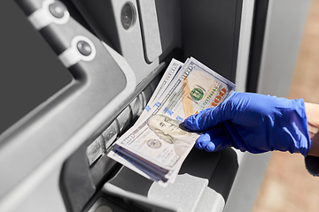 Image showing hand in medical glove with money at atm machine