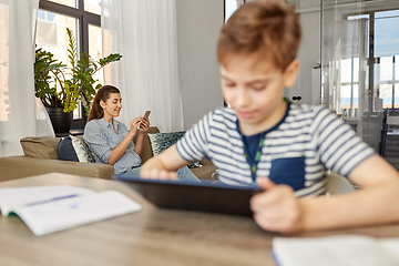 Image showing mother with smartphone and son learning at home