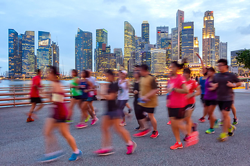 Image showing Joggers on illuminated Singapore promenade