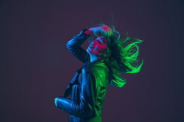 Image showing Beautiful woman\'s portrait with blowing hair on dark studio background in colorful neon light