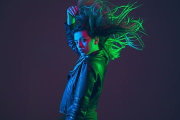 Image showing Beautiful woman\'s portrait with blowing hair on dark studio background in colorful neon light