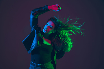 Image showing Beautiful woman\'s portrait with blowing hair on dark studio background in colorful neon light