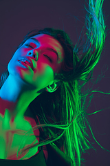 Image showing Beautiful woman\'s portrait with blowing hair on dark studio background in colorful neon light