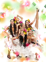 Image showing Beautiful young women in carnival costumes in colorful neon lights on white background in flying confetti