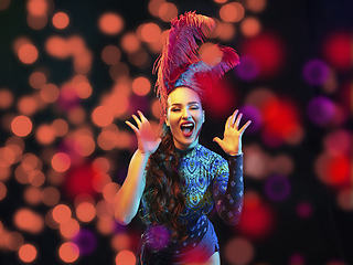 Image showing Beautiful young woman in carnival and masquerade costume in colorful neon lights on black background in flying confetti