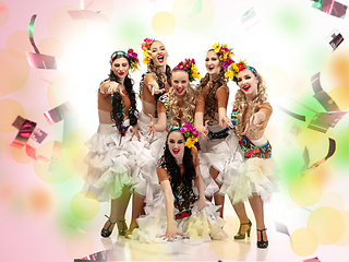 Image showing Beautiful young women in carnival costumes in colorful neon lights on white background in flying confetti