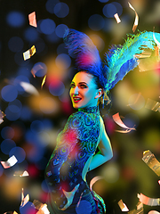 Image showing Beautiful young woman in carnival and masquerade costume in colorful neon lights on black background in flying confetti