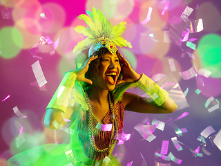 Image showing Beautiful young woman in carnival and masquerade costume in colorful neon lights on gradient background in flying confetti