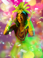 Image showing Beautiful young woman in carnival and masquerade costume in colorful neon lights on gradient background in flying confetti