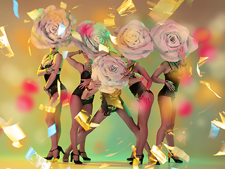 Image showing Young female dancers with huge floral hats in neon light on gradient background in flying confetti