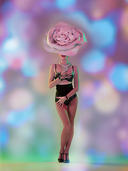 Image showing Young female dancer with huge floral hat in neon light on gradient background in flying confetti