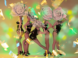 Image showing Young female dancers with huge floral hats in neon light on gradient background in flying confetti