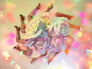 Image showing Young female dancers with huge floral hats in neon light on gradient background in flying confetti, top view