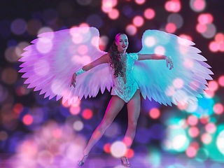 Image showing Young female dancer with angel\'s wings in neon light on black background in flying confetti