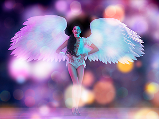 Image showing Young female dancer with angel\'s wings in neon light on black background in flying confetti