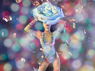 Image showing Young female dancer with huge floral hat in neon light on gradient background in flying confetti