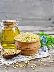 Image showing Bran flaxseed in bowl with oil in jar on old board