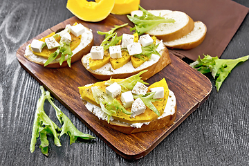 Image showing Bruschetta with pumpkin and arugula on dark board