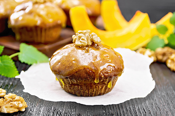 Image showing Cupcake pumpkin with orange glaze and walnuts on dark board