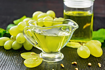 Image showing Oil grape in gravy boat on dark board