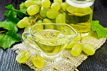 Image showing Oil grape in gravy boat on wooden board