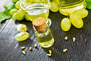 Image showing Oil grape in vial on dark board