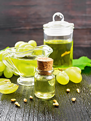 Image showing Oil grape in vial on dark wooden board