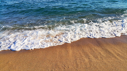 Image showing Sea wave with white foam on the coastal sand