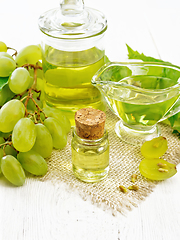 Image showing Oil grape in vial on light wooden board