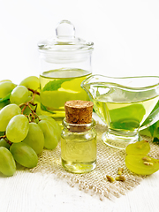 Image showing Oil grape in vial on wooden board