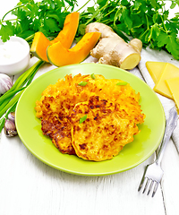 Image showing Pancakes of pumpkin with cheese in green plate on white wooden b