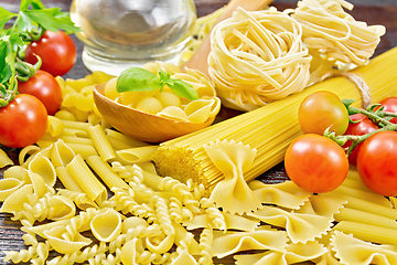 Image showing Pasta different with oil and tomatoes on wooden board