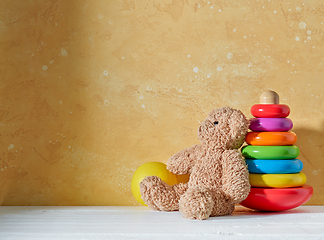 Image showing old teddy bear and wooden toy on a wooden shelf