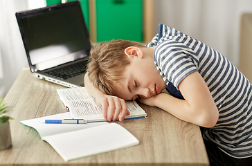 Image showing tired student boy sleeping on desk at home