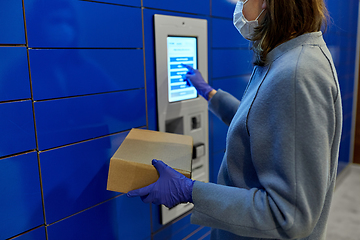 Image showing woman in mask with box at parcel machine