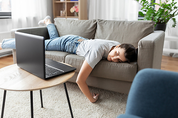 Image showing bored woman with laptop lying on sofa at home