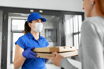 Image showing delivery girl in mask giving pizza boxes to woman