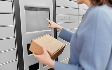 Image showing smiling woman with box at automated parcel machine