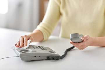 Image showing close up of woman cleaning desk phone with tissue