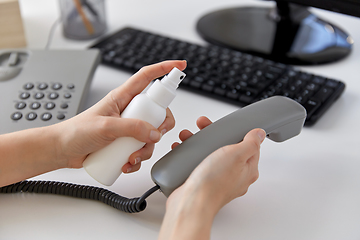 Image showing close up of woman cleaning phone with sanitizer