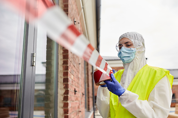 Image showing healthcare worker sealing door with caution tape