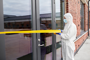 Image showing healthcare worker sealing door with caution tape