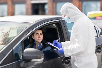 Image showing healthcare worker with clipboard and woman in car